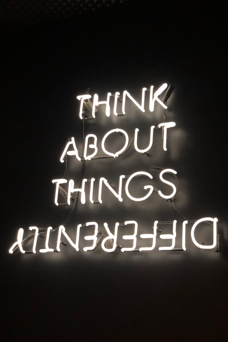 A glowing neon sign displaying an upside-down motivational quote against a dark background.